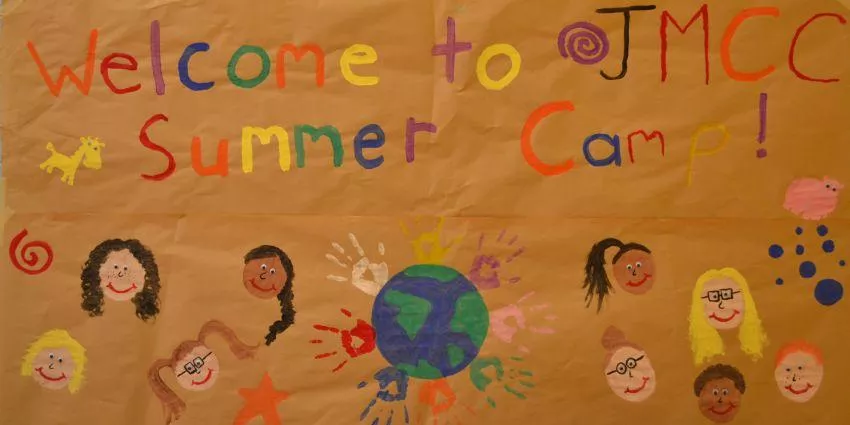 Colorful hand-painted poster welcoming to JMCC Summer Camp with faces and globe with handprints.