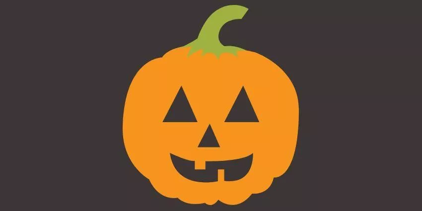 Orange pumpkin with green stem carved with triangular eyes, nose, and smiling mouth against dark background