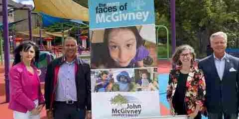 Four people standing outdoors next to a John McGivney Children's Centre banner with a child’s photo.