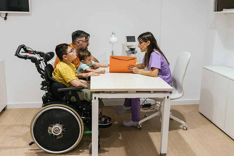 Father and his two sons, one using a wheelchair, attending a medical consultation