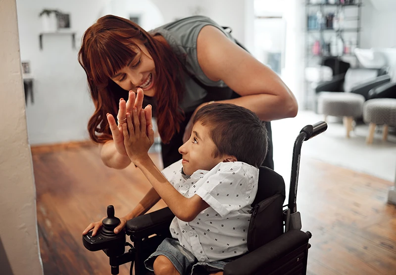 Hairdresser high fiving child in hair salon