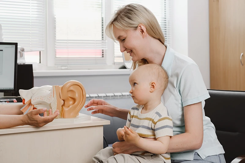 Mother with infant child visiting audiologist