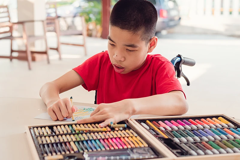 Disabled boy colouring with crayons