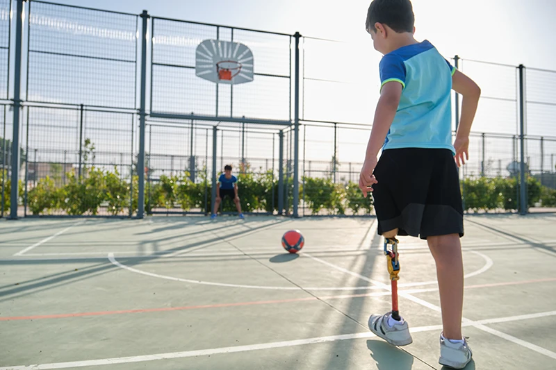 Boy with leg prosthesis  kicking a ball