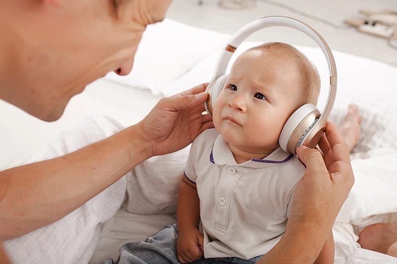 Father holding headphones on babies head