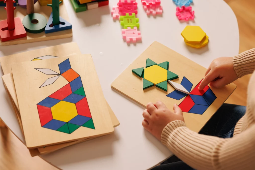 Child assembling colorful geometric shapes on a wooden board matching design patterns.